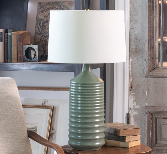 Green wavy lamp on a side table next to books