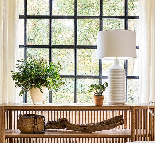 Tall wavy white table lamp on an open wooden console table