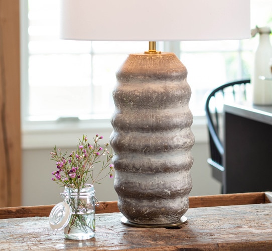 Textured brown ceramic table lamp next to a mason jar with pink flowers