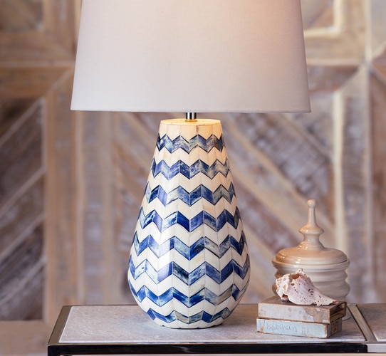Tapered bone and blue table lamp net to a shell on a side table