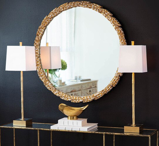 Thin gold buffet lamp spaced evenly around a gold olive branch mirror