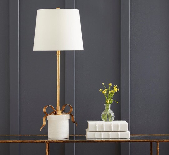Gold buffet lamp with a thin bow at the alabaster base next to two books