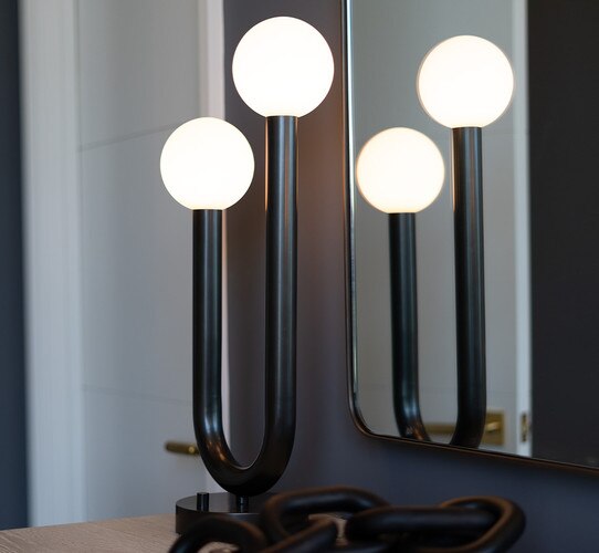 Black two armed modern table lamp in front of a mirror