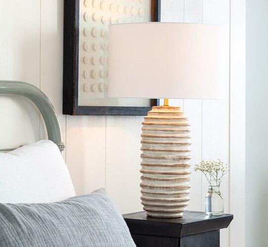 Wood table lamp with flaking white paint on a bedside table