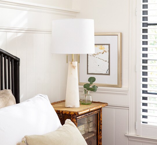 Tall alabaster table lamp with dual on and off chain on a bedside table