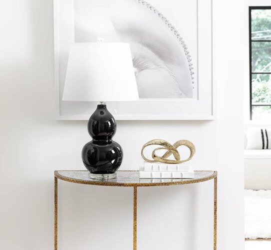 Demilune holding black table lamp and brass sculpture