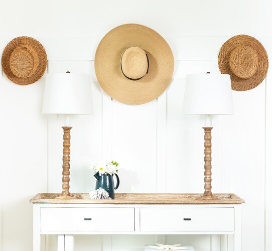 Rustic wood buffet lamps on a sideboard with a blue watering can closest to the lamp on the left