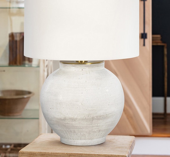 White ceramic table lamp with textured glazing on a wooden side table