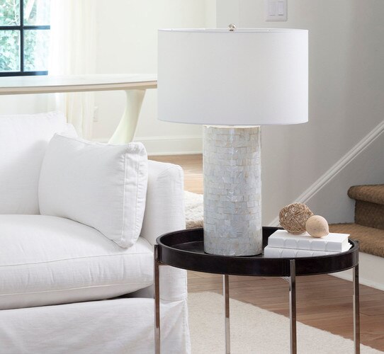 Cylindrical mother of peark table lamp on a black leather side table