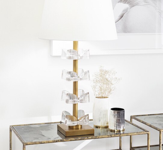 Gold table lamp with tiered glass flowers on a console table