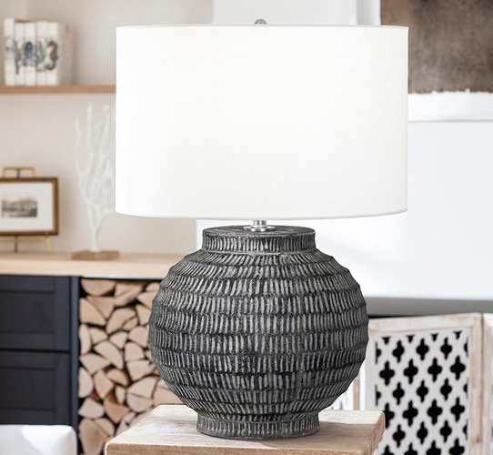 Black textured table lamp with wide ceramic base on a wood side table