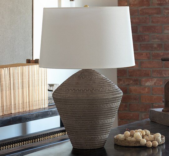 Brown table lamp with carved texture on a wood console table
