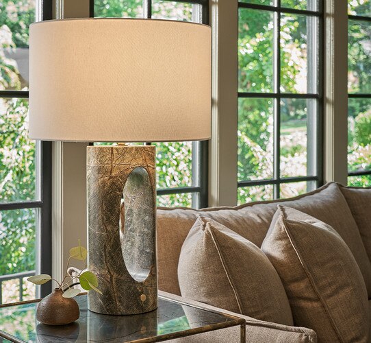 Green marble table lamp with empty center on a side table next to a sofa