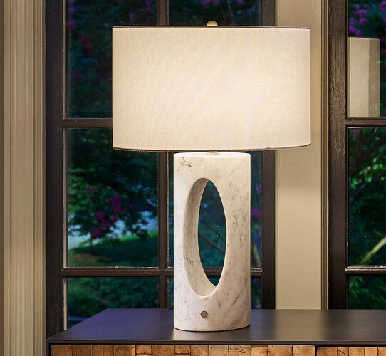 White marble table lamp with an open center on a wooden console table