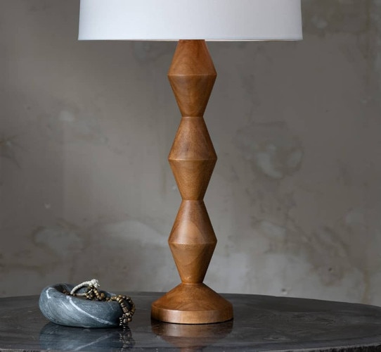 Wood table lamp on a petrified wood table next to a small marble bowl