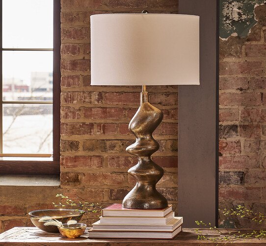 ORganically shaped gold metal lamp stood on a stack of books