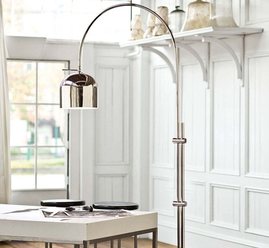 Nickel arc floor lamp above a white desk