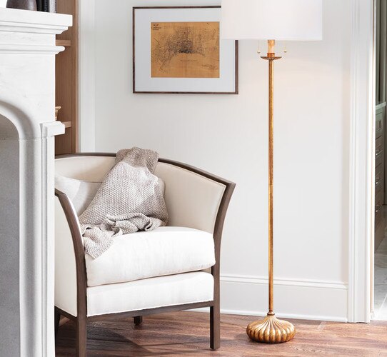 A gold lamp next to a white chair