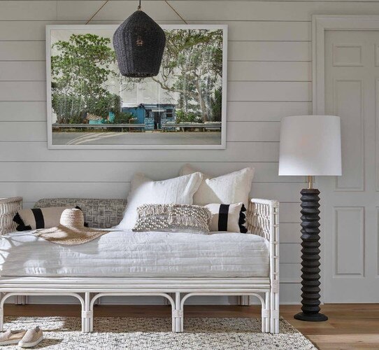 Black wooden floor lamp next to a white linen day bed