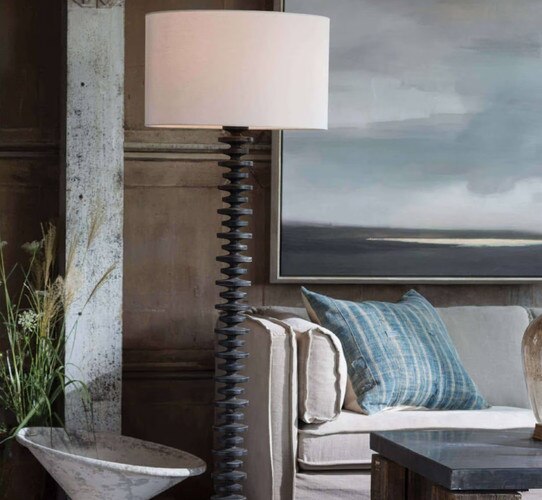 Black Wood table lamp next to a large couch in front of a landscape painting