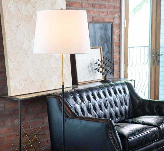 Gold and black table lamp in front of a black leather couch