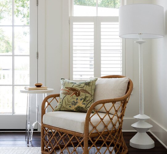 White floor lamp next to rattan chair