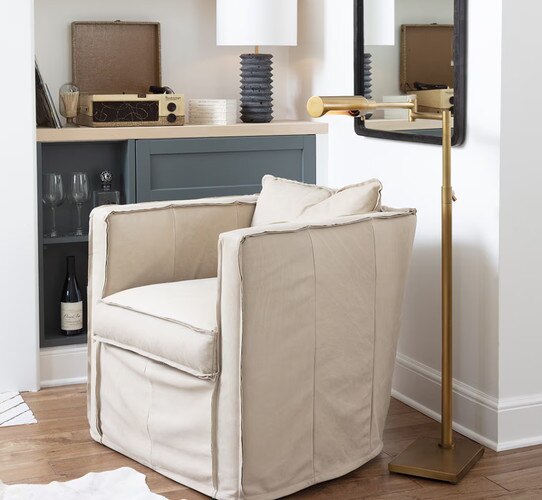 Brass task lamp beside a linen swivel chair