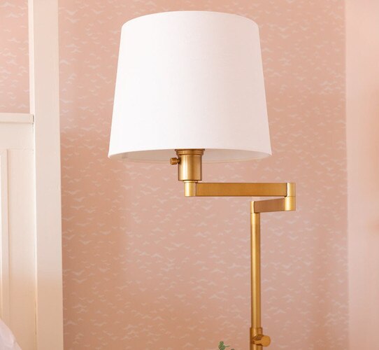 Brass task floor lamp in front of a pink wall