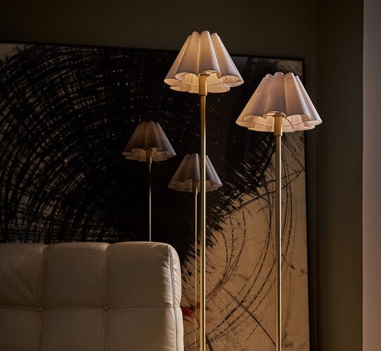 Brass dual floor lamp next to white leather chair