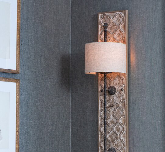 Wood paneled wall sconce with textured panel and rustic metal base