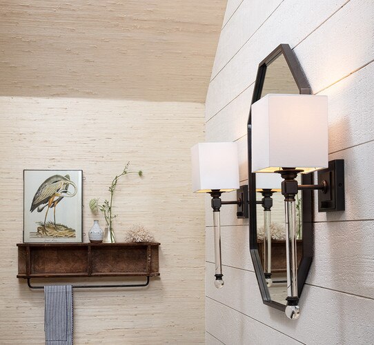 Crystal and bronze wall sconce beside a black mirror