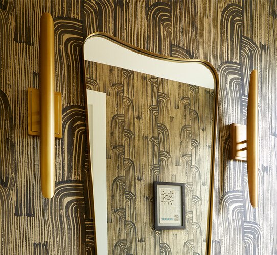 Brass wall sconces flankinging a brass bathroom vanity mirror