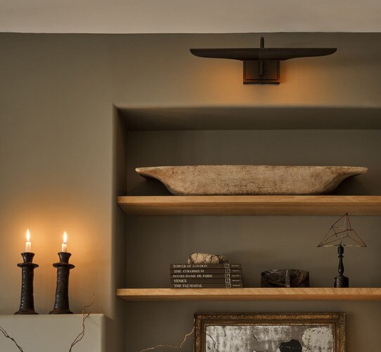 Black picture light above a built in shelf with decor