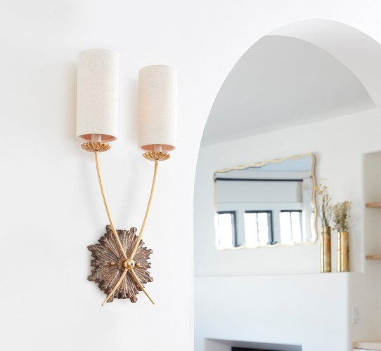Double armed traditional gold wall sconce with a mirror in the background