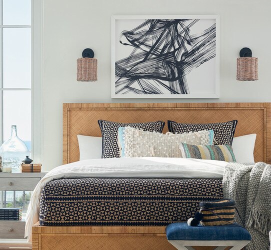 Pink rattan sconces with black base above a rattan bed