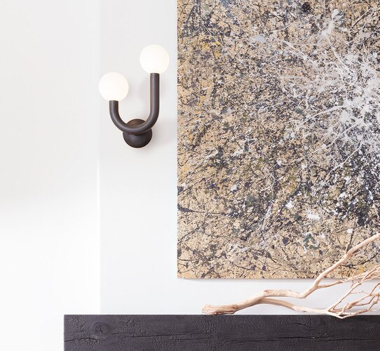 Double armed bronze sconce next to an abstract brown and white painting