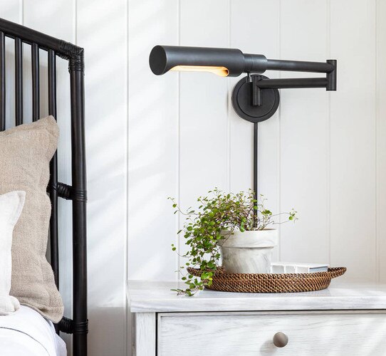 Bronze task sconce above a nighstand with a tray