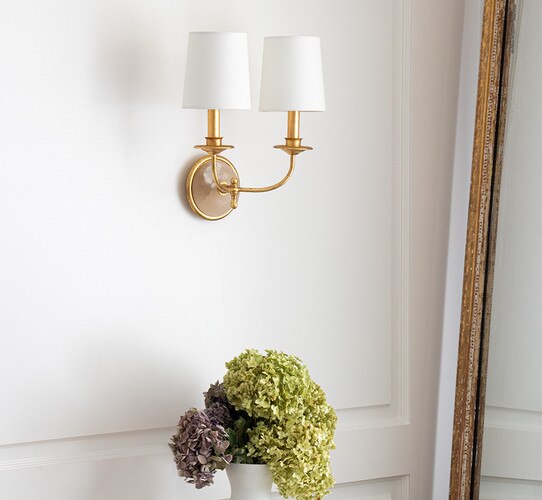 Double armed wall sconce with an alabaster base above a base of hydrangeas