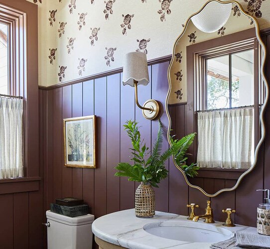 Bathroom with maroon bead board, sconce and wavy gold mirror