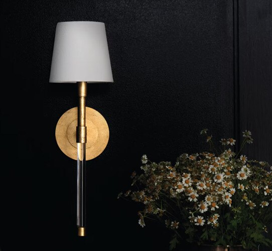 Antique gold and crystal wall sconce next to a vase of yellow and white flowers