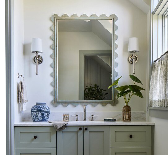 Polished nickel wall sconces flanking a large bathroom mirror