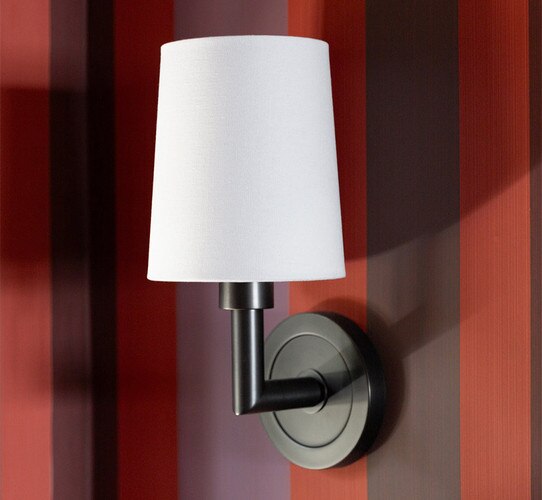 Bronze wall sconce on a striped red brown and purple wall