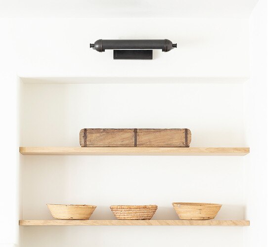 Black picture light above two built in shelves with bowls