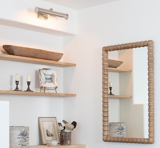 Polished nickel picture lamp above wooden shelves with decor