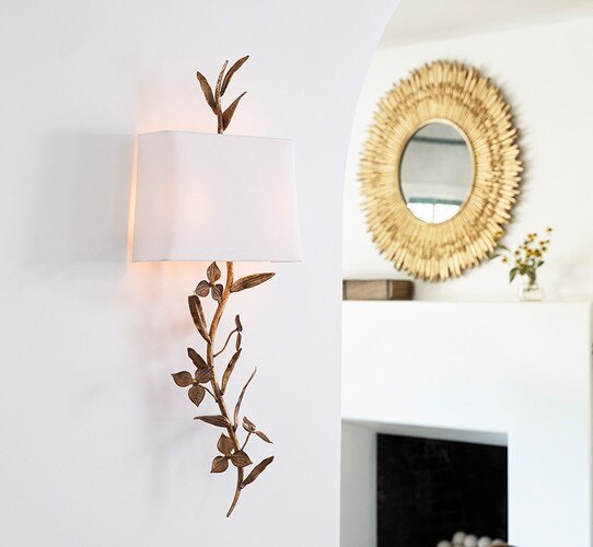 Gold sconce in the shape of a branch of flowers with a shade flush with the wall