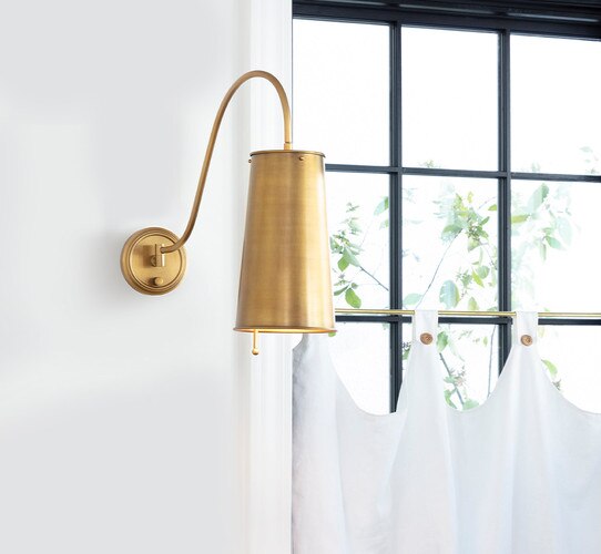 Brass sconce on a wall next to a window