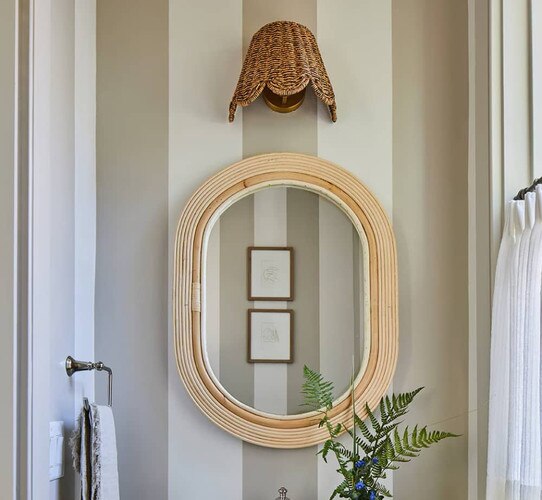 Wicker mirror with a sconce above it