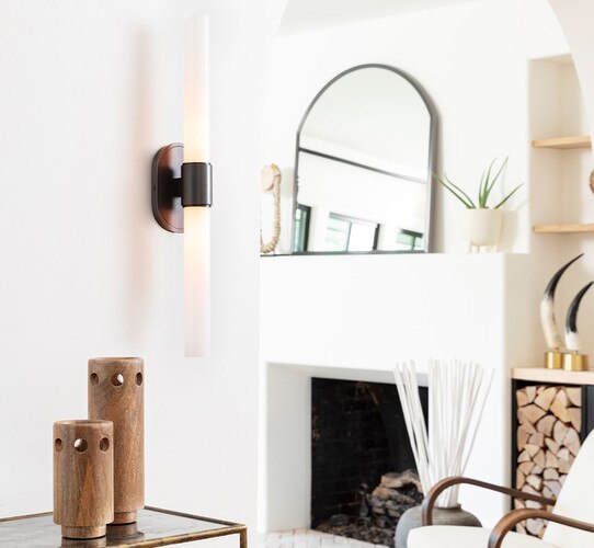 double wick sconce above a console table with two wood vases