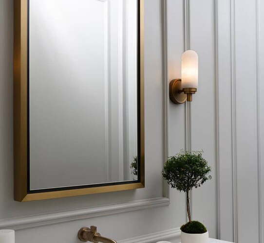Brass bathroom mirror with a alabaster sconce beside it