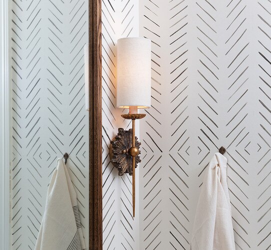 Traditional gold wall sconce next to a wooden mirror